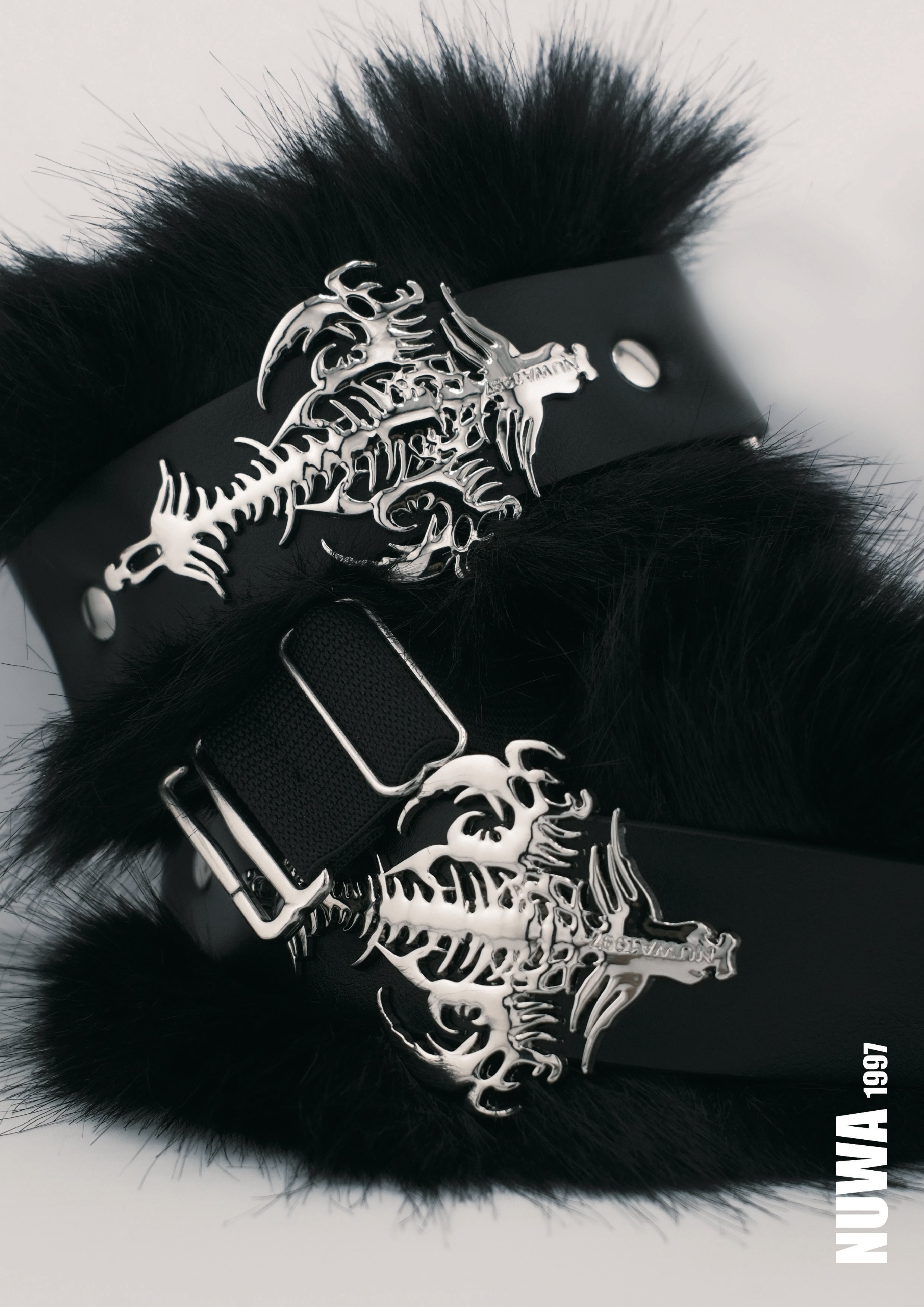 Black faux fur cuffs with silver metal dragon skeleton buckles, displayed on a light gray background.