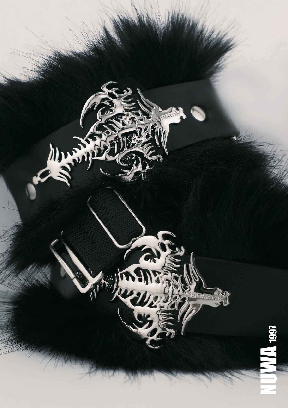 Black faux fur cuffs with silver metal dragon skeleton buckles, displayed on a light gray background.