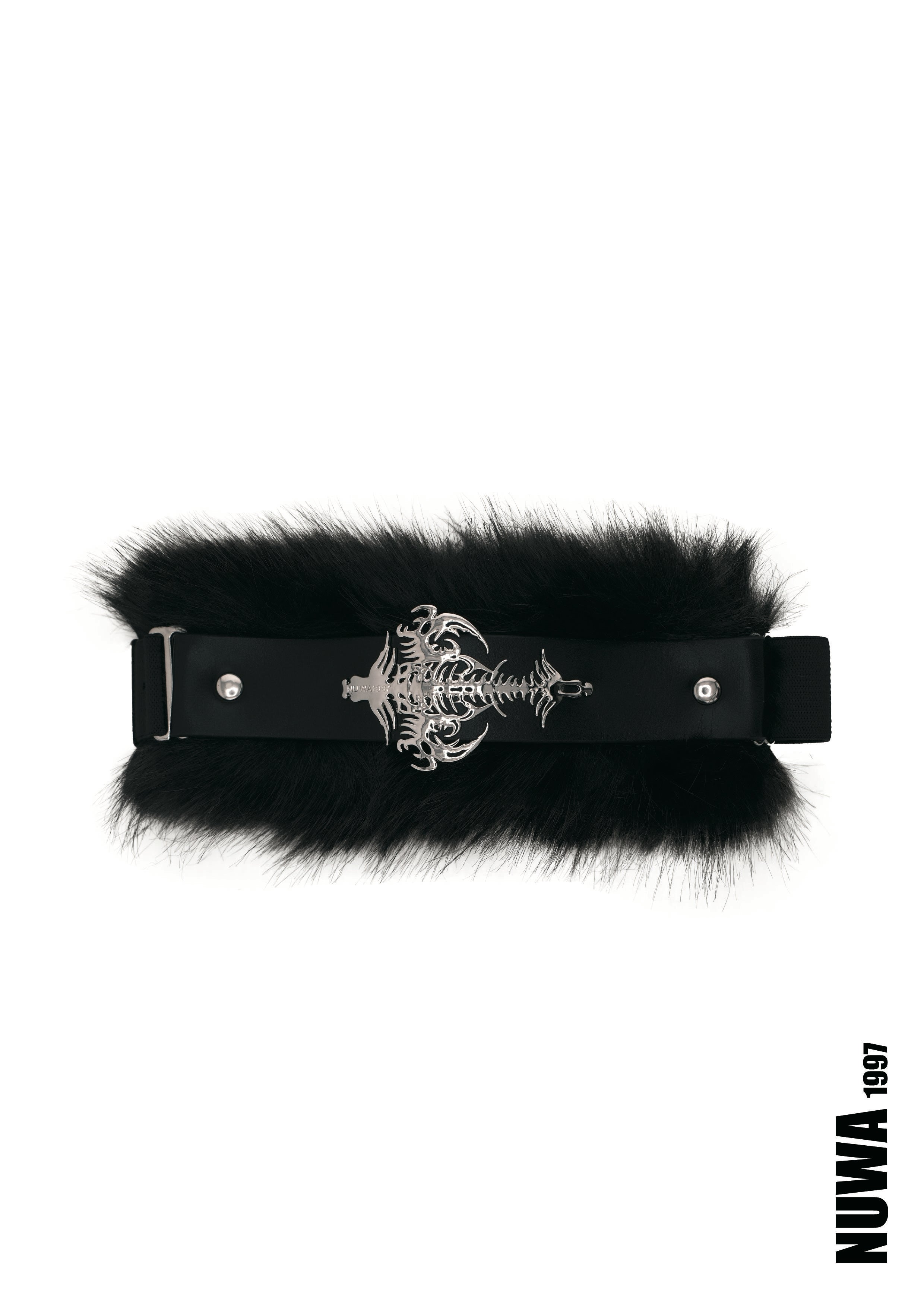 A black faux-fur belt with a black leather strap and a prominent silver-toned metal buckle featuring a skull and crossbones design, shown against a plain white background.