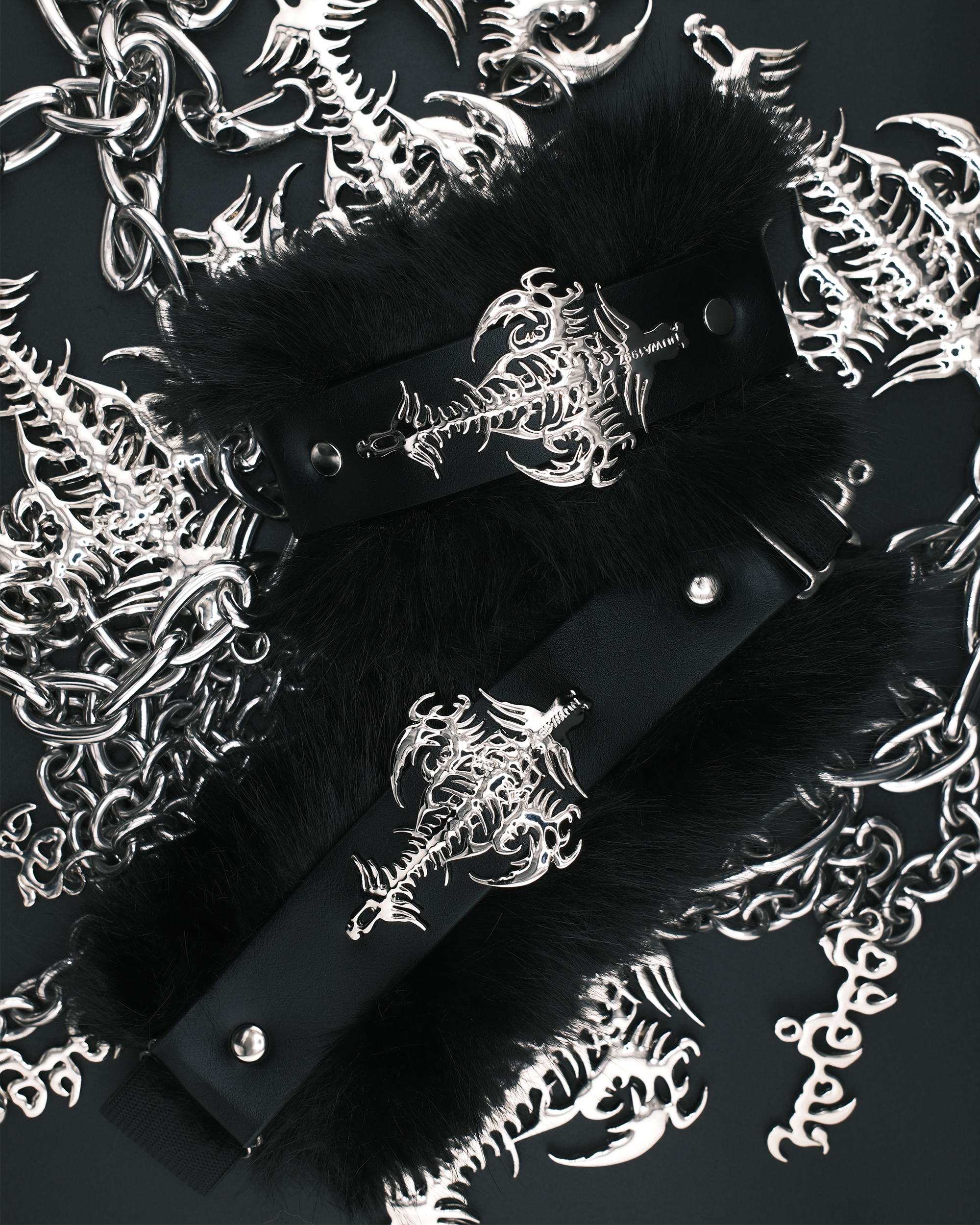 Black faux-fur trimmed choker collar with a black strap and silver gothic skeleton keyhole centerpiece, displayed on a dark background surrounded by matching silver skeleton chain and bone motifs.